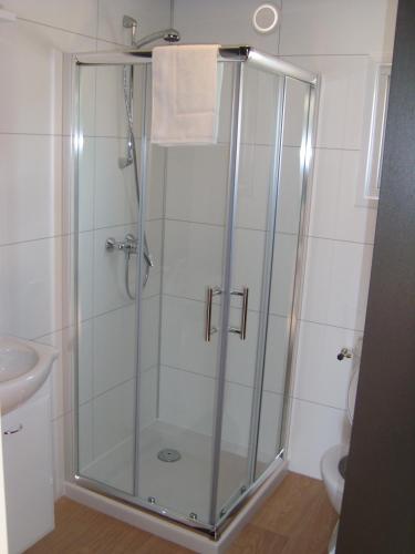 a shower with a glass door in a bathroom at Luxe Strandhuisje, dagelijks verse broodjes en extra's inbegrepen in Wijk aan Zee