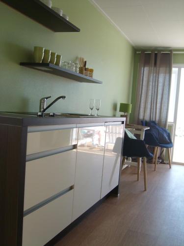 a kitchen with a sink and a table with wine glasses at Luxe Strandhuisje, dagelijks verse broodjes en extra's inbegrepen in Wijk aan Zee