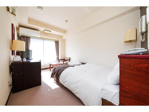 Un dormitorio con una cama blanca con un teléfono. en Sky Heart Hotel Koiwa - Vacation STAY 49101v en Tokio