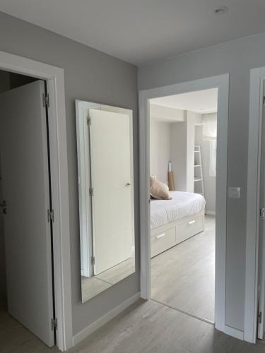 a white bedroom with a mirror and a bed at Golden Views in Viveiro