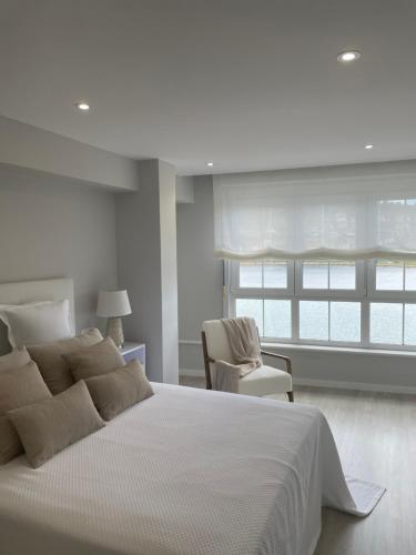 a white bedroom with a large bed and a chair at Golden Views in Viveiro