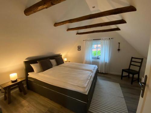 sypialnia z łóżkiem, krzesłem i oknem w obiekcie Pilsumer Lohne Huus w mieście Krummhörn