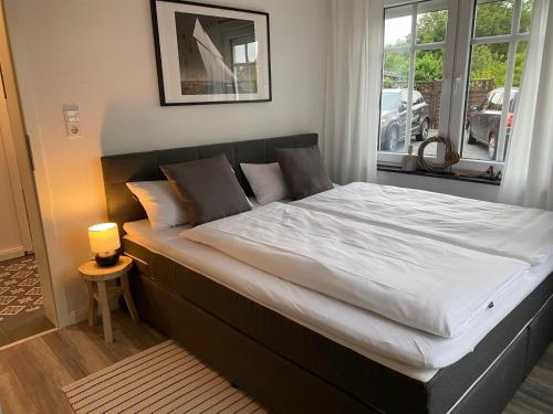 a bedroom with a large bed with white sheets at Pilsumer Lohne Huus in Krummhörn