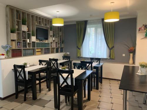 uma sala de jantar com mesas e cadeiras e uma televisão em Sunny Hotel em Lviv