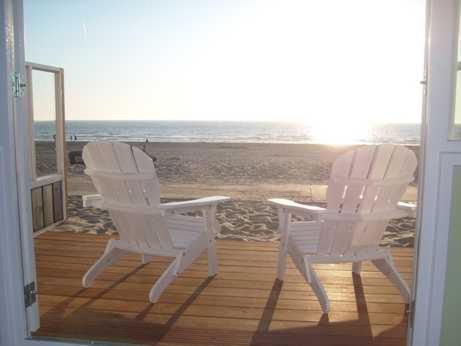 two white chairs sitting on a porch overlooking the beach at Luxe Strandhuisje op het strand van Wijk aan Zee met wifi in Wijk aan Zee