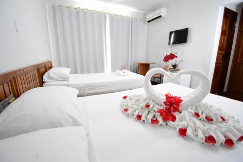 pokój hotelowy z 2 białymi łóżkami z 2 łabędzami w obiekcie Hotel Jalim w mieście Caldas Novas