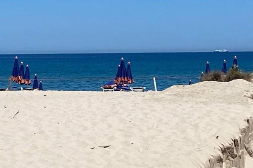 a beach with chairs and umbrellas and the ocean at Arboria Sun & Sea in Sorso