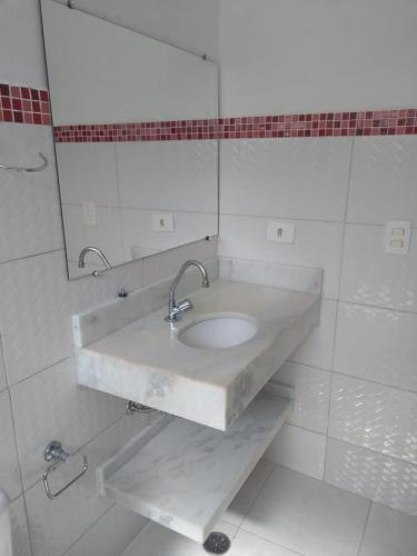 a white bathroom with a sink and a mirror at Vila do Aconchego in Ubatuba