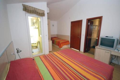 a bedroom with a bed and a tv and a room at BMV TRIPLE ROOM WITH BALCONY in Sveti Stefan