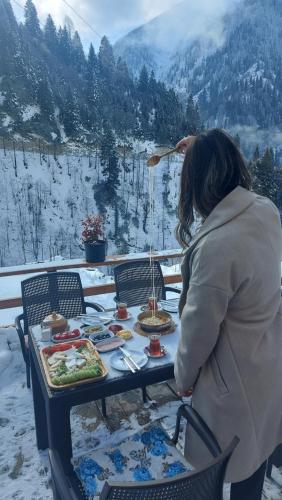 Una mujer sentada en una mesa en la nieve. en Yayla Bungalov, en Ayder