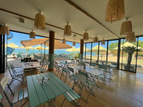 a restaurant with tables and chairs and windows at Pelso Camping in Alsóörs