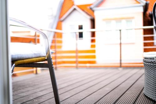 a chair on a deck with a house in the background at Anker Self-Check-In Hotel in Lindau
