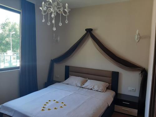 1 dormitorio con 1 cama grande y lámpara de araña en Вила Мая 2, en Krayni Dol