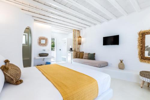 a white bedroom with a bed and a couch at Evlalia Studios & Villas in Skopelos Town
