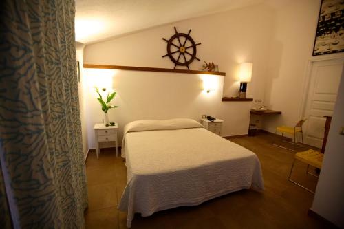 a bedroom with a bed and a clock on the wall at Hotel Villa Pimpina in Carloforte