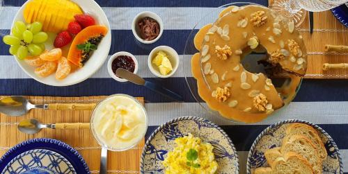 een tafel met borden vol eten en een donut erop. bij Pousada Três Coqueiros in Praia do Bananal