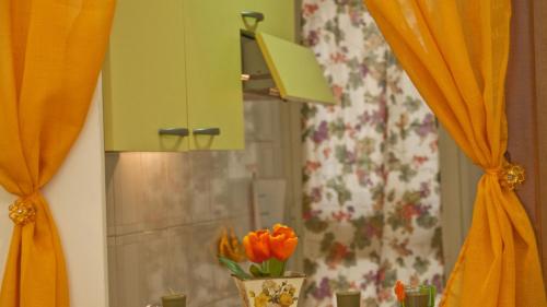 lustro z pomarańczowymi zasłonami i wazonem z pomarańczowymi kwiatami w obiekcie Rental in Rome Celeste Apartment w Rzymie