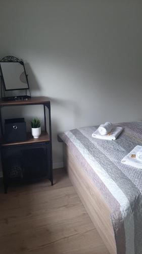 een slaapkamer met een bed en een tafel met een spiegel bij Apartament Miętowa Perła in Kołobrzeg