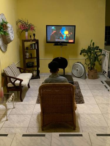 a man sitting in a chair in a living room watching tv at Hostal familiar Villa Nome in Penonomé