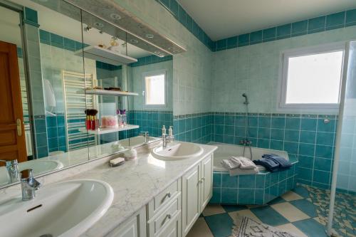 - une salle de bains carrelée de bleu avec deux lavabos et une baignoire dans l'établissement Chambre privée de 12m² dans une maison toute équipée, à Aureilhan