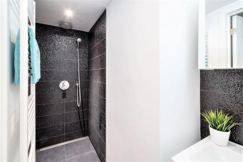 baño con ducha de azulejos negros en Beautiful Terrace Apartment in the Heart of Antwerp, en Amberes