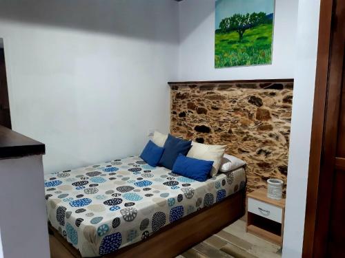 1 dormitorio con 1 cama con pared de piedra en Apartamentos Callampa, en Torrejón el Rubio