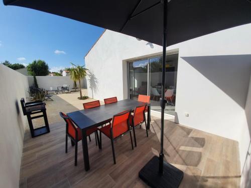 une table et des chaises avec un parasol sur une terrasse dans l'établissement Le clos des baigneurs, à Dolus-d'Oléron