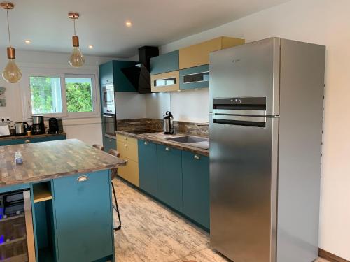 a kitchen with blue cabinets and a stainless steel refrigerator at CapriBeach in Pornichet