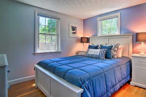 a bedroom with a blue bed with two windows at Cape Cod Bungalow with Patio Less Than 1 Mi to Beaches! in West Yarmouth