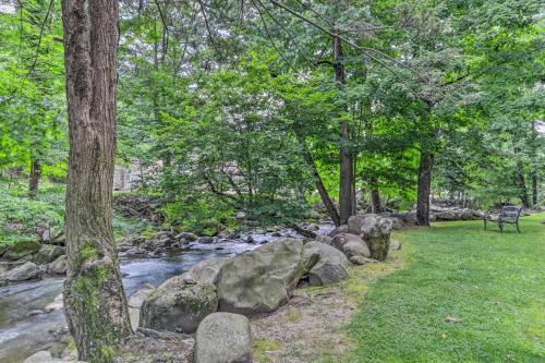 a park bench next to a river with rocks and trees at Waterfall/6th‑Floor View/Walk Downtown in Gatlinburg