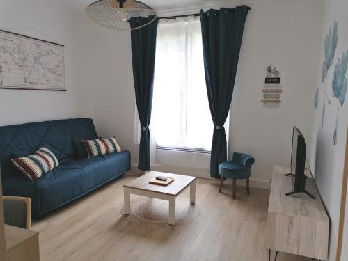 ein Wohnzimmer mit einem blauen Sofa und einem Tisch in der Unterkunft Les Marguerites, maison proche de Chambord in Bracieux