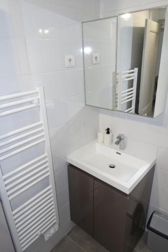 une salle de bain blanche avec un lavabo et un miroir dans l'établissement Maison Carrée/Coeur historique de Nîmes - Superbe Appt 55m², à Nîmes