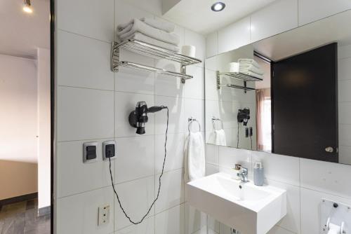 Baño blanco con lavabo y espejo en Tribeca Silver - Ex habitación de hotel sin cocina, en Santiago