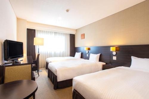 a hotel room with two beds and a flat screen tv at Art Hotel Hirosaki City in Hirosaki