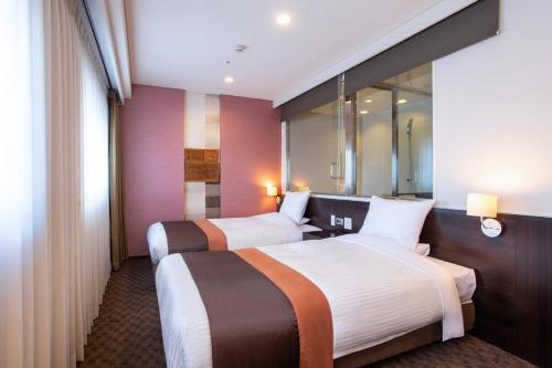 弘前市にあるアートホテル弘前シティのベッド2台と鏡が備わるホテルルームです。