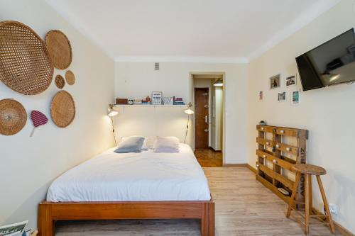 um quarto com uma cama e uma televisão de ecrã plano em Studio avec balcon, plage à 50m, proche Vieux Port em Marselha