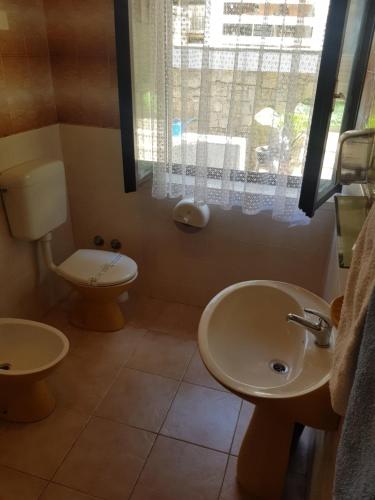 a bathroom with a sink and a toilet and a window at Studio apartman in Meljine
