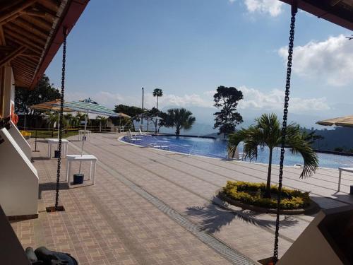 a swimming pool with a palm tree next to a building at Hotel Takuara in Vergara