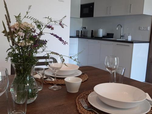 a table with plates and glasses and a vase with flowers at Apartmán Studnice in Nové Město na Moravě