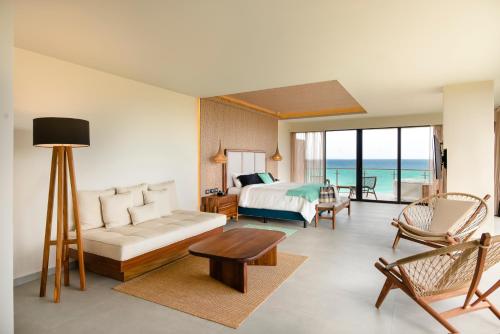 a living room with a bed and a bedroom with the ocean at Mvngata Beach Hotel in Playa del Carmen