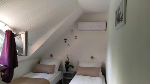 two beds in a room with white walls at Arcadia Guesthouse in Ábrahámhegy