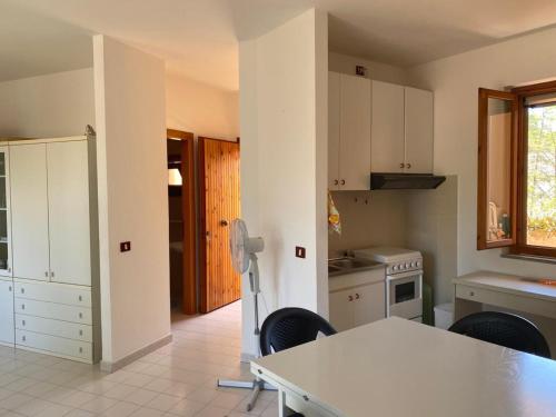 uma cozinha com armários brancos e uma mesa e cadeiras em Arboria Sun & Sea em Sorso