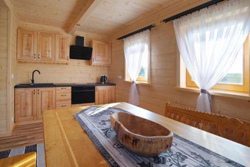 a kitchen with a wooden table with a wooden bowl on it at Domek na farmie in Szaflary