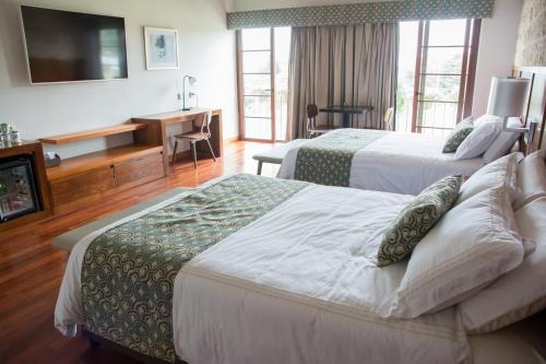 a hotel room with two beds and a television at Los Brezos Hotel Boutique in Volcán