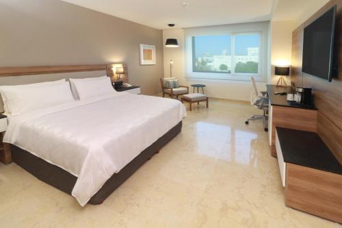 um quarto grande com uma cama grande e uma televisão em Holiday Inn & Suites - Puerto Vallarta Marina & Golf, an IHG Hotel em Puerto Vallarta