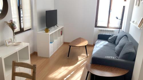 sala de estar con sofá azul y TV en Apartamento The Wall Xperience en León