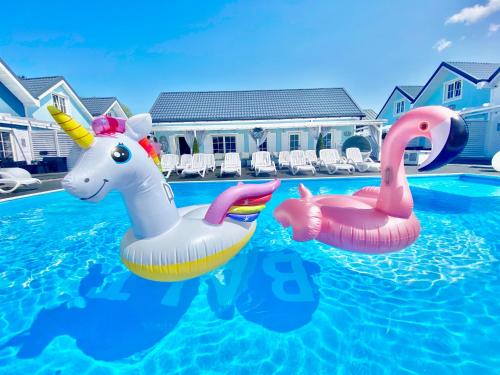 two inflatable swans in a swimming pool at Domki BALTIC FAMILY basen kidsclub rowery in Mielno