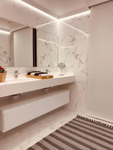 a white bathroom with a sink and a mirror at CANELAS PREMIUM NUEVOS con PISCINA, AMPLIAS TERRAZAS Y GARAJE in Portonovo
