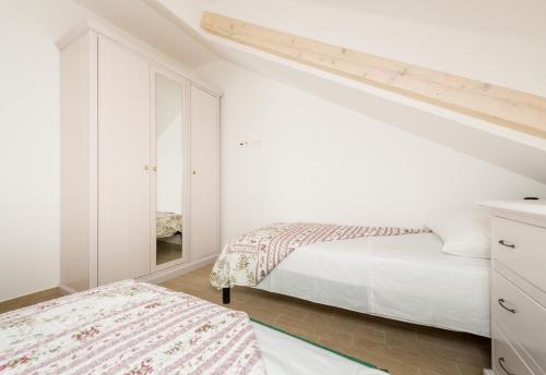 a white bedroom with two beds and a mirror at Stone House Domacin Old Town in Dubrovnik