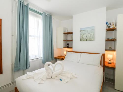 ein Schlafzimmer mit einem weißen Bett mit zwei weißen Bögen in der Unterkunft Harbour Catch Cottage in Weymouth